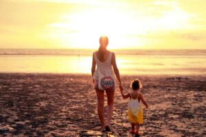 Vrouw met kind op het strand, tijdens de zonsondergang